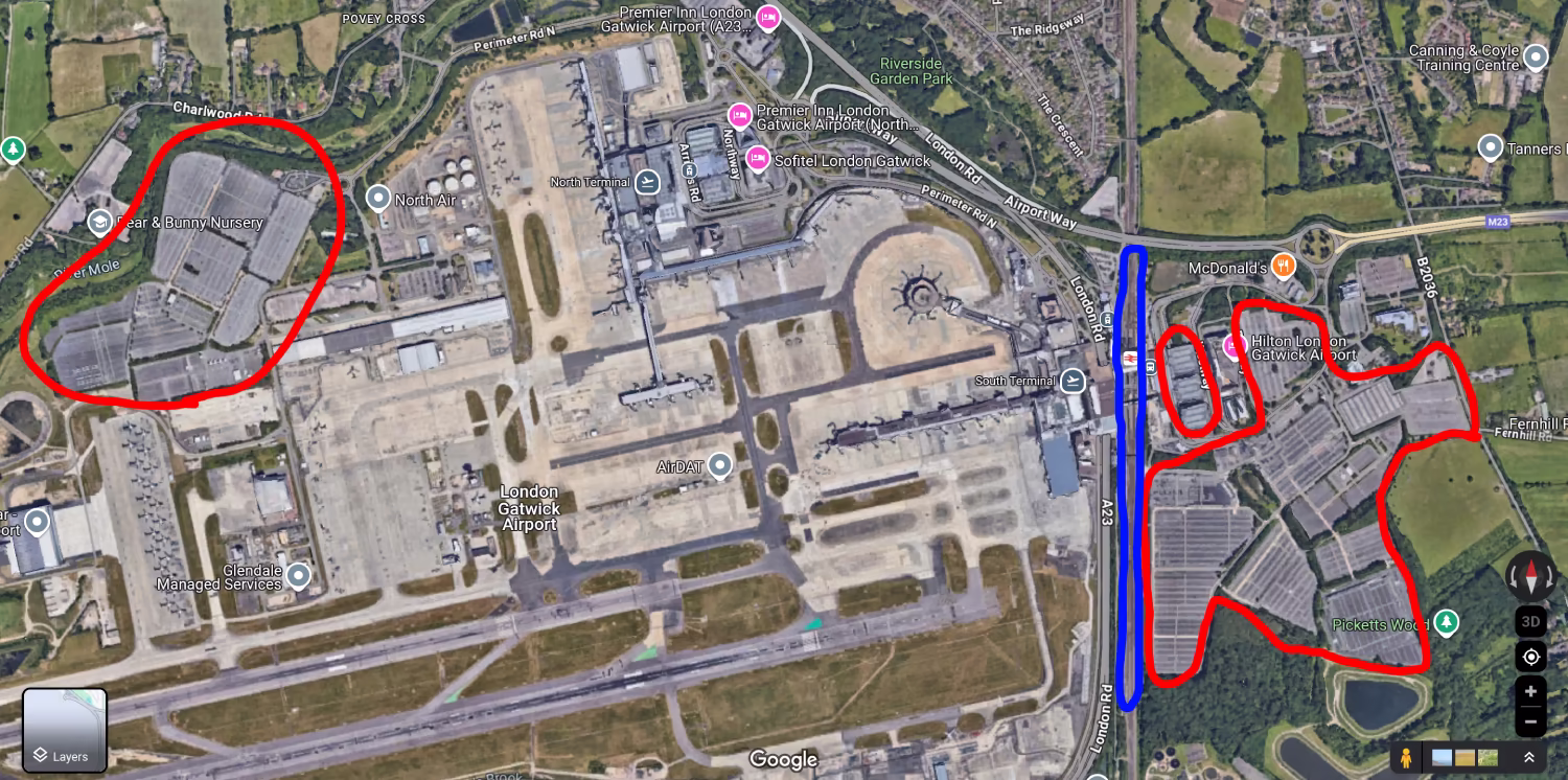 An aerial view of London Gatwick Airport. The various car parks (short-stay, long-stay, holiday parking) are circled in red, and the train line in blue. The train station is located next to the South terminal, whereas the car parks are located further out to the bottom-right and up in the top-left, and take up roughly 10-20x as much space.